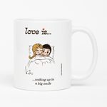 Load image into Gallery viewer, Front view: Love is... waking up to a big smile personalized ceramic mug by Kim Casali.
